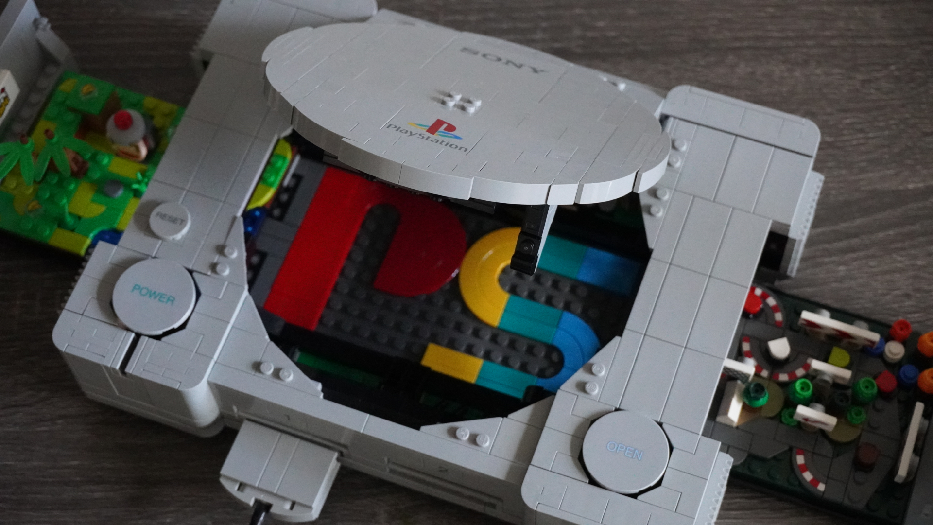 Open retro LEGO PlayStation-style console with gray panels and colorful interior components visible inside, including a blue, yellow, and red arrangement.