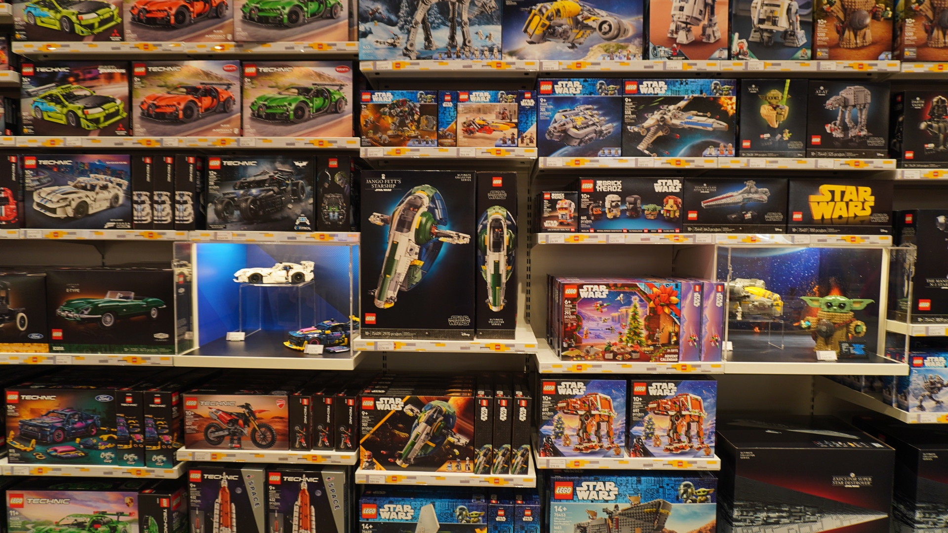 Shelf full of LEGO and Star Wars sets on display in a toy store, colorful boxes arranged in rows.