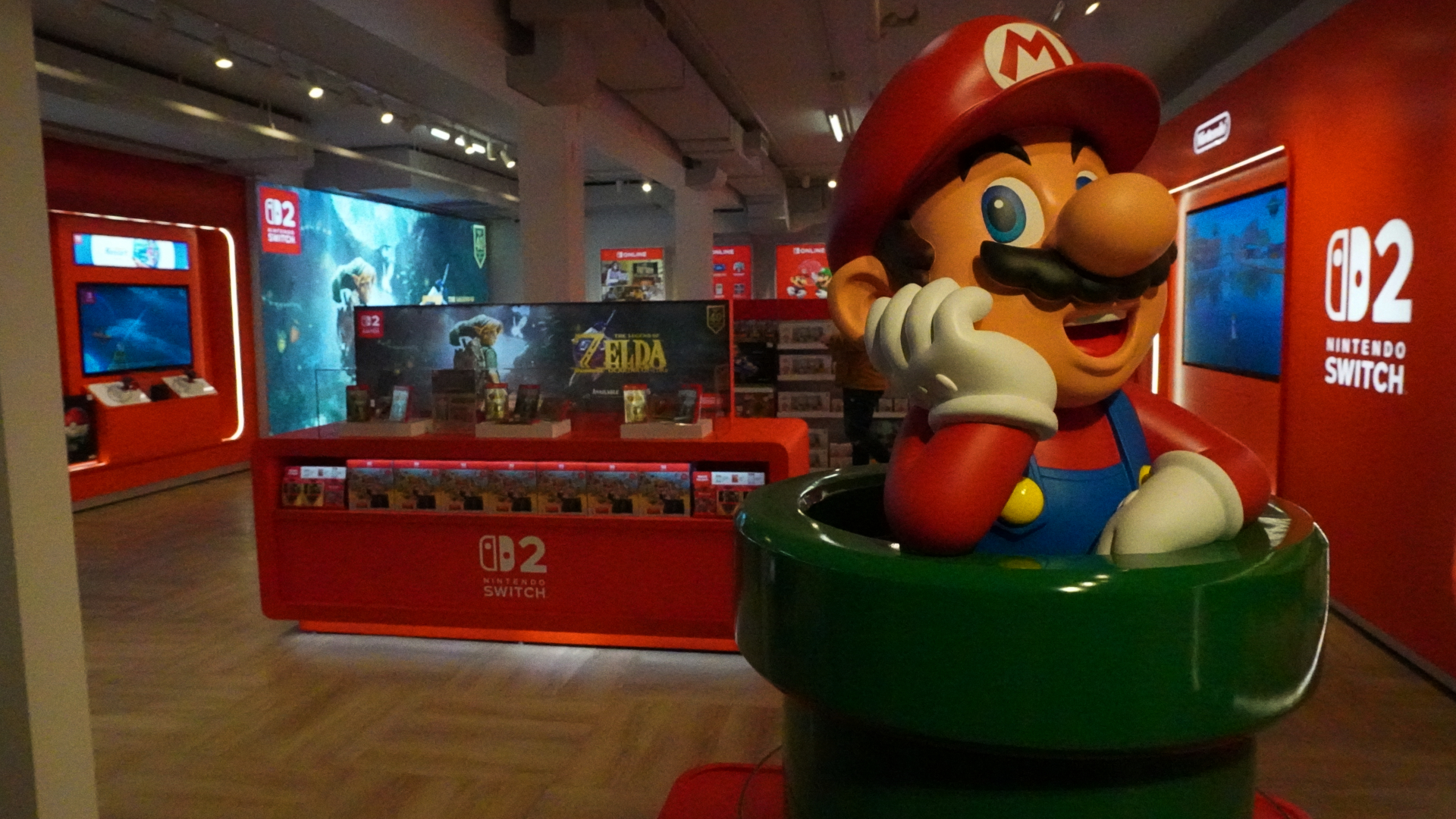 Nintendo-Store-1 1 | iPhone in Canada Life-size Mario statue in a red display area at a Nintendo Switch exhibit, with game kiosks and signage in the background.