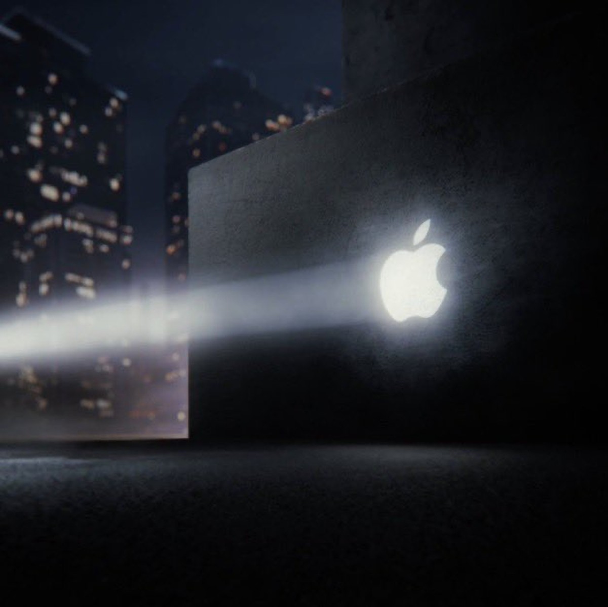 John Ternus teaser showing a glowing Apple logo on a MacBook-shaped wall